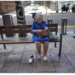 elderly woman sitting on public seat with one shoe off, in Madrid Spain