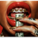 Extreme close-up of glossy red lips with gold braces biting a rolled US dollar bill, held by tattooed fingers with long gold glitter nails against a vivid red background, symbolising wealth, luxury and consumerism.