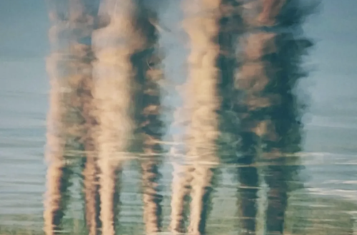 Atmospheric abstract photograph by Carmen Zamos, showing elongated, blurred human figures reflected across a glassy surface in soft blue, teal, peach and cream tones.Atmospheric abstract photograph by Carmen Zamos, showing elongated, blurred human figures reflected across a glassy surface in soft blue, teal, peach and cream tones.