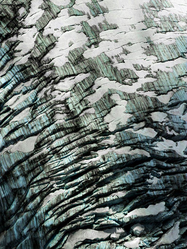 Jimmy Chin aerial photograph revealing intricate blue-green crevasses, ridges and snow across the fractured surface of a glacier.